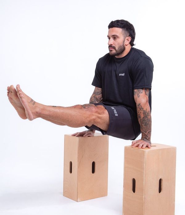 Man performing a controlled strength exercise in a dark, minimalist gym.